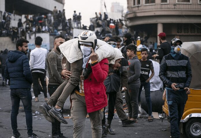 شاب يحمل مصاب من متظاهرين ثورة تشرين في ساحة حافظ القاضي، تصوير فاروق الجمل